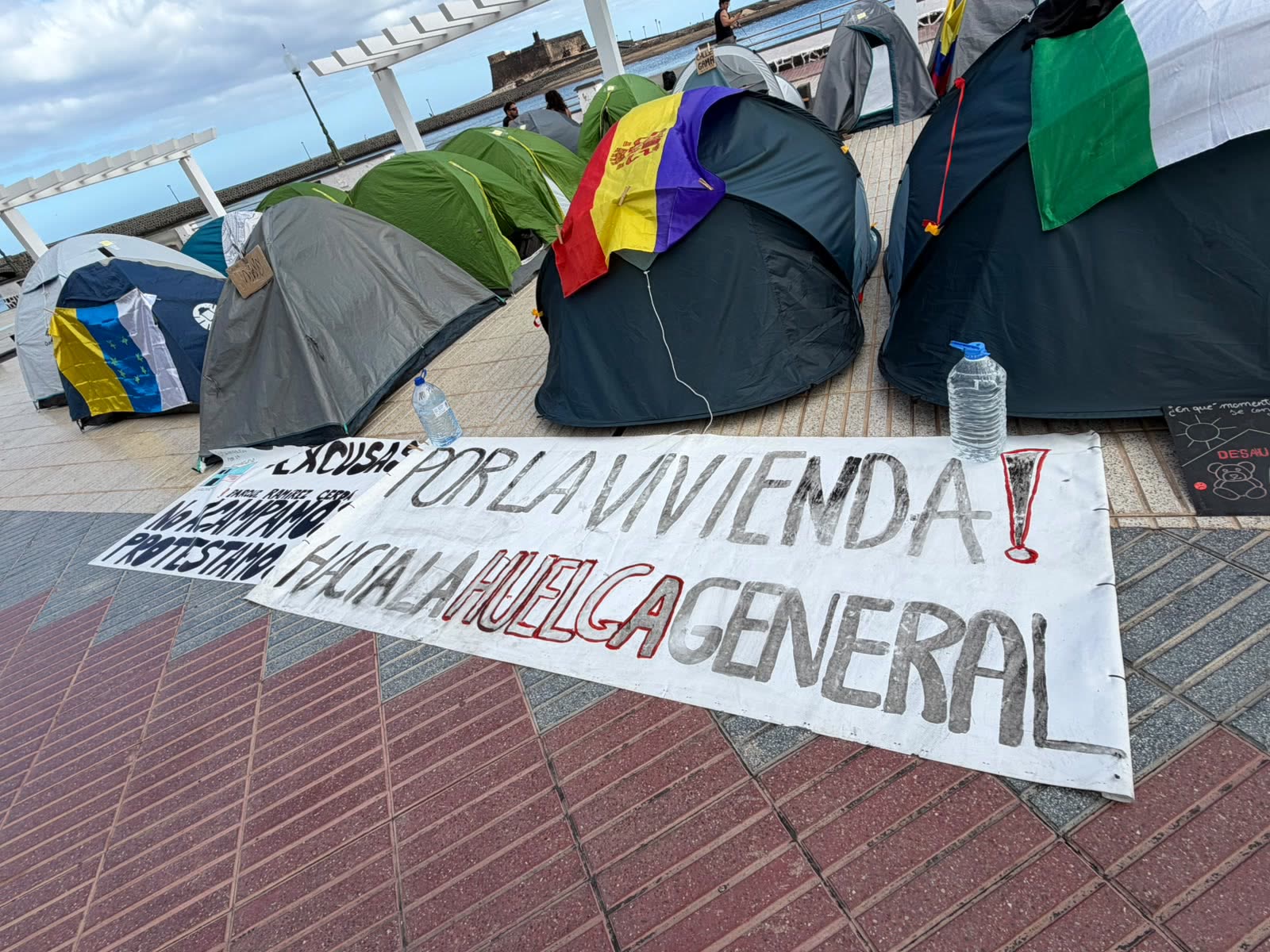 Tiendas de campaña en el parque con una pancarta: «¡Por la vivienda! Hacia la huelga general»