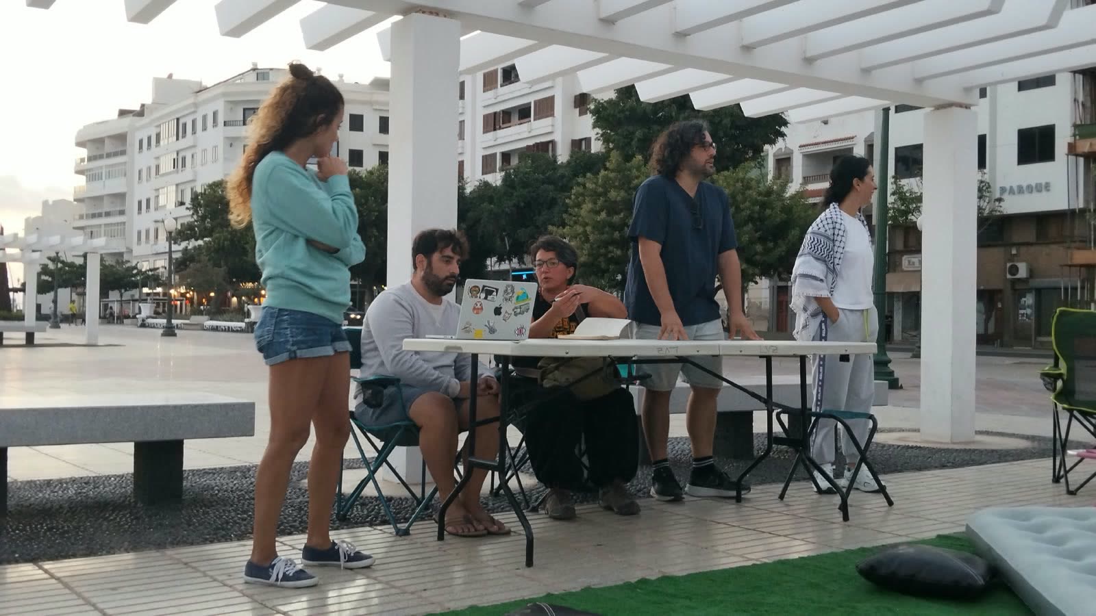 Una mesa con gente alrededor en la pérgola, al atardecer