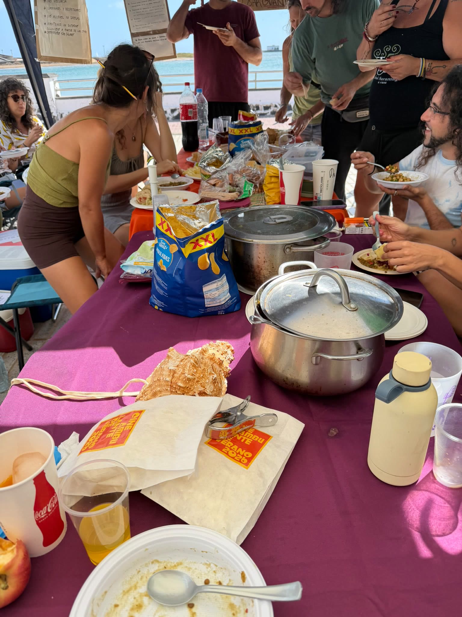 La mesa del enyesque con ollas, platos y gente sirviéndose