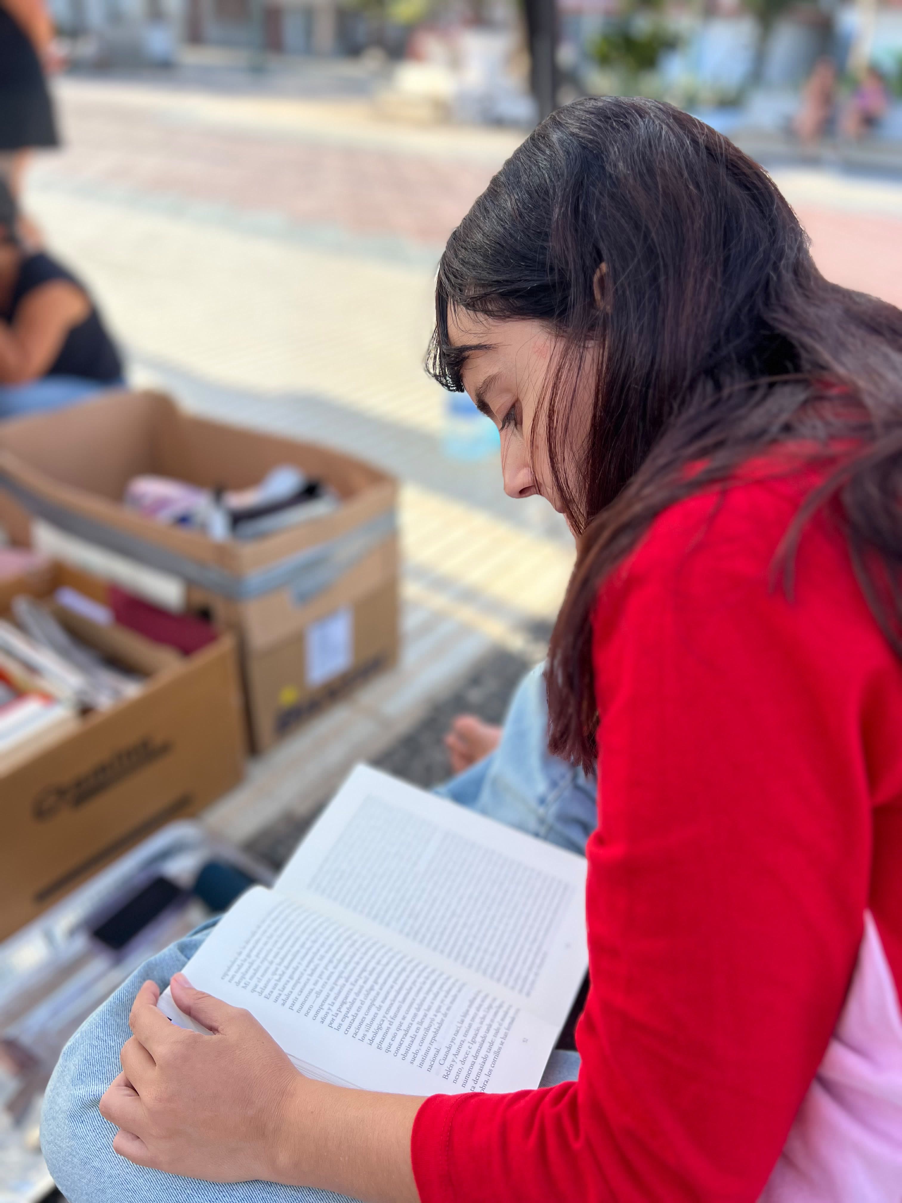 Una persona leyendo junto a las cajas de libros